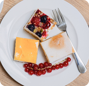 Drei Stück Kuchen mit Beeren, Sahne und Quark auf einem Teller mit Gabel.